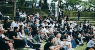 Penonton duduk di area tribun terbuka