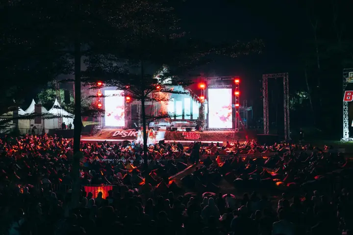 Penonton memadati area konser malam dengan cahaya panggung merah