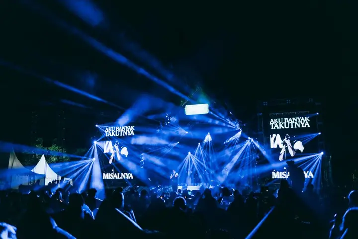 Sorot lampu biru di atas penonton konser malam